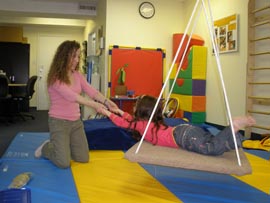 Child on a platform swing during therapy