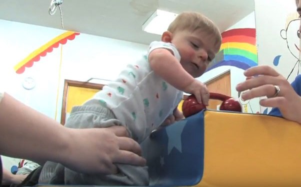 Baby on a caregiver's knees doing hand activities